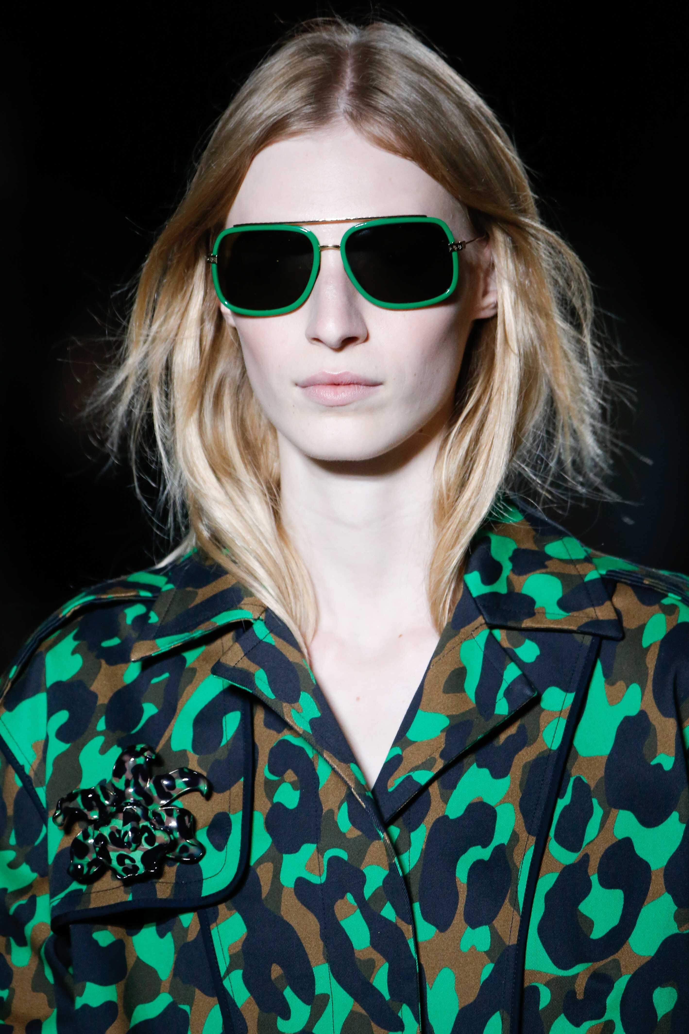 Blonde hair: Front facing view of a woman wearing green sunglasses with ash blonde hair colour.