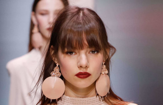 woman on the runway with a long fringe hairstyle wearing a pastel pink outfit
