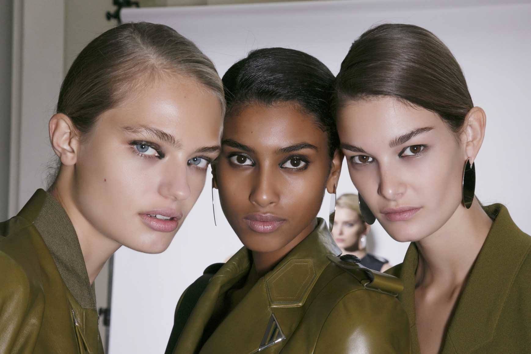 keratin hair treatment Q&A: close up shot of three models with sleek, smooth hair, wearing all green and posing backstage at a fashion show