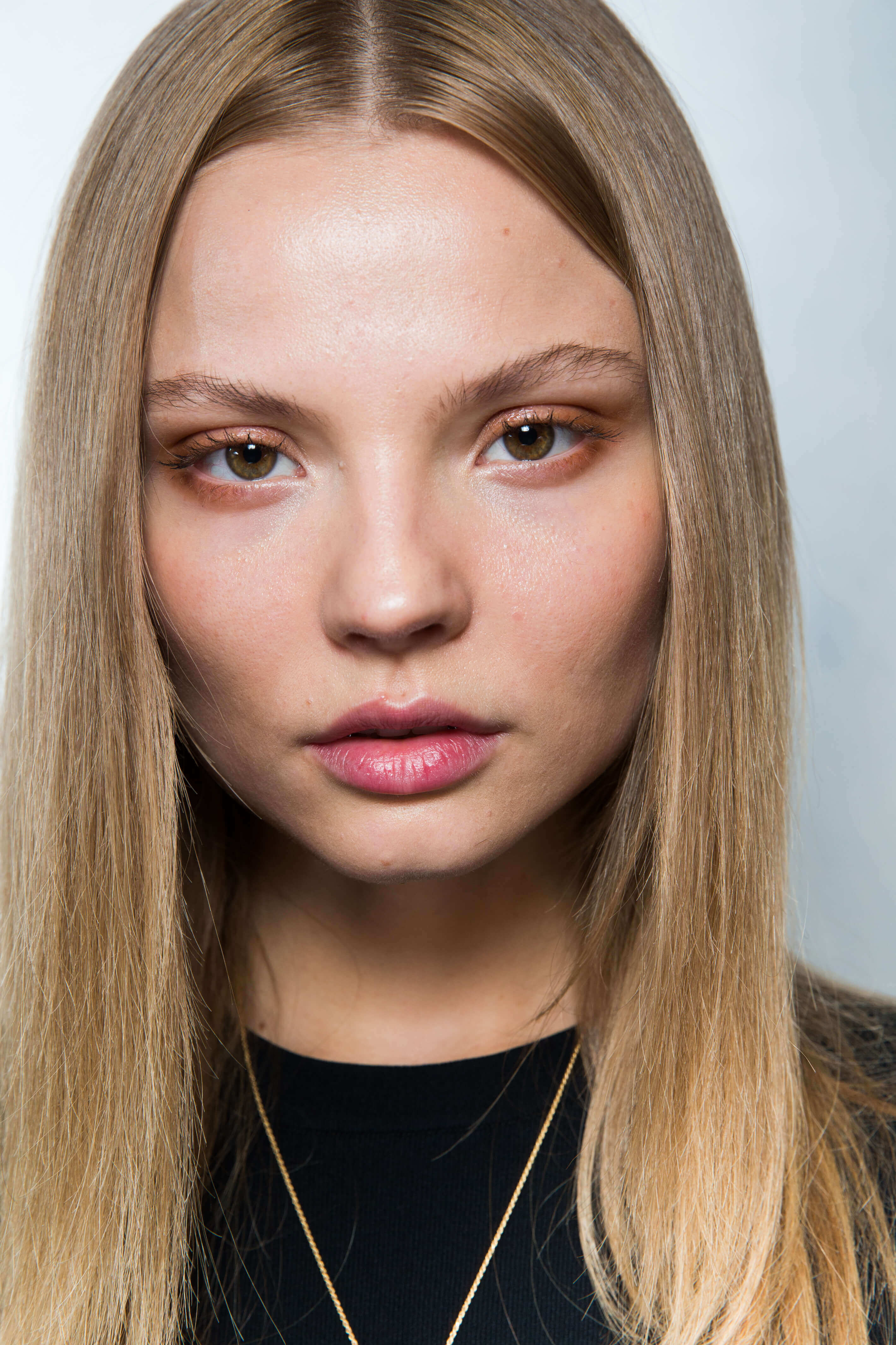 keratin hair treatment: close up shot of model with straight, long dark blonde hair. posing backstage at a fashion show