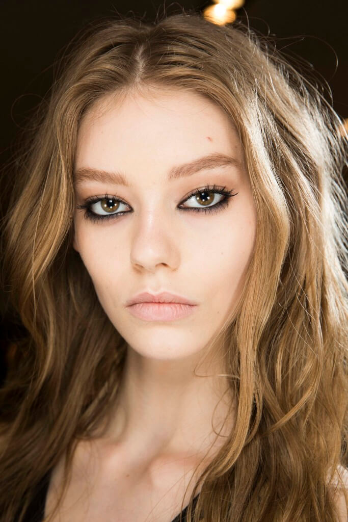 Best hairstyles for round faces: Close up of a woman with medium brown wavy hair and layers