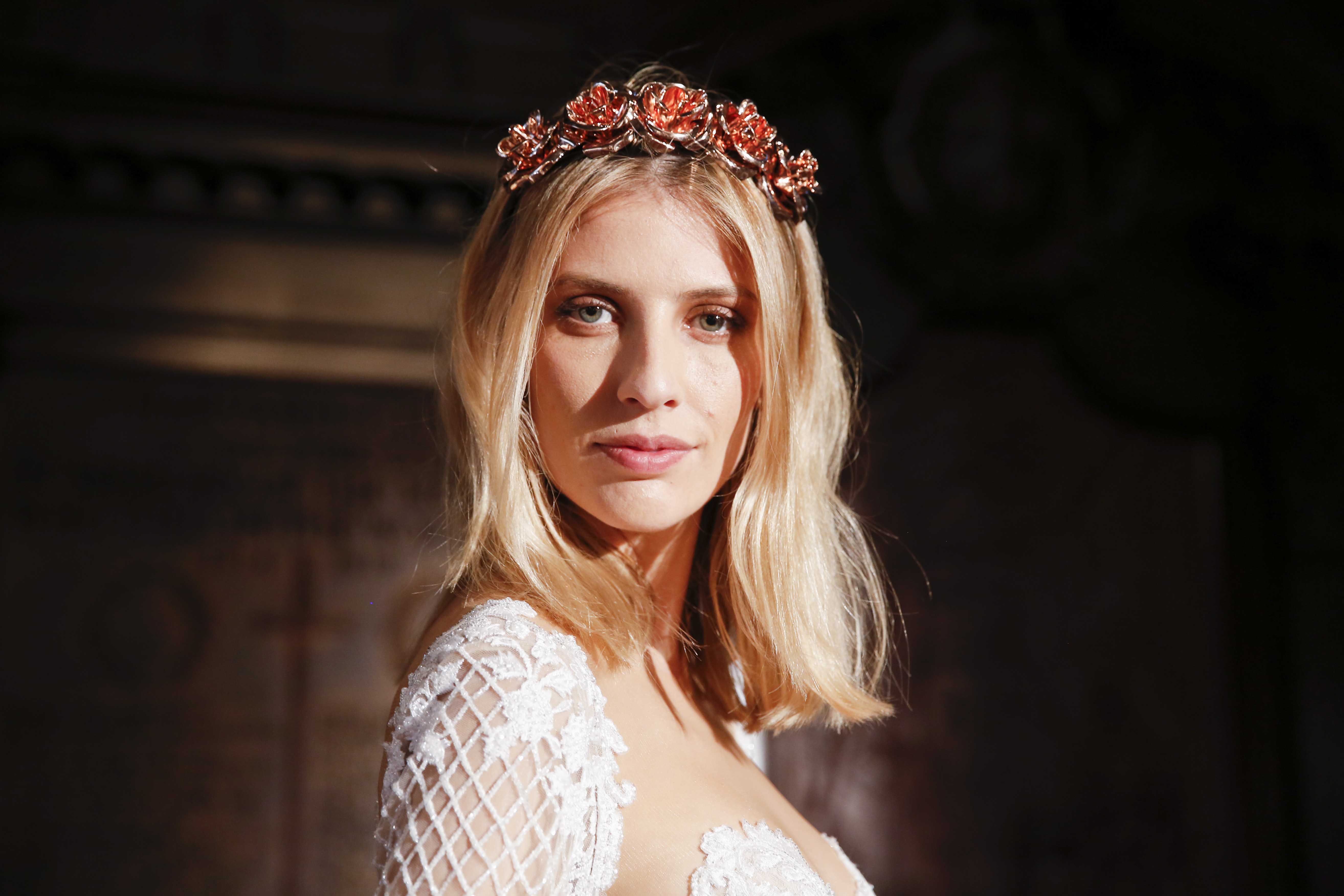 Wedding hairstyles for short hair: Woman with blonde wavy long bob with red headband accessoryy wearing a wedding dress.