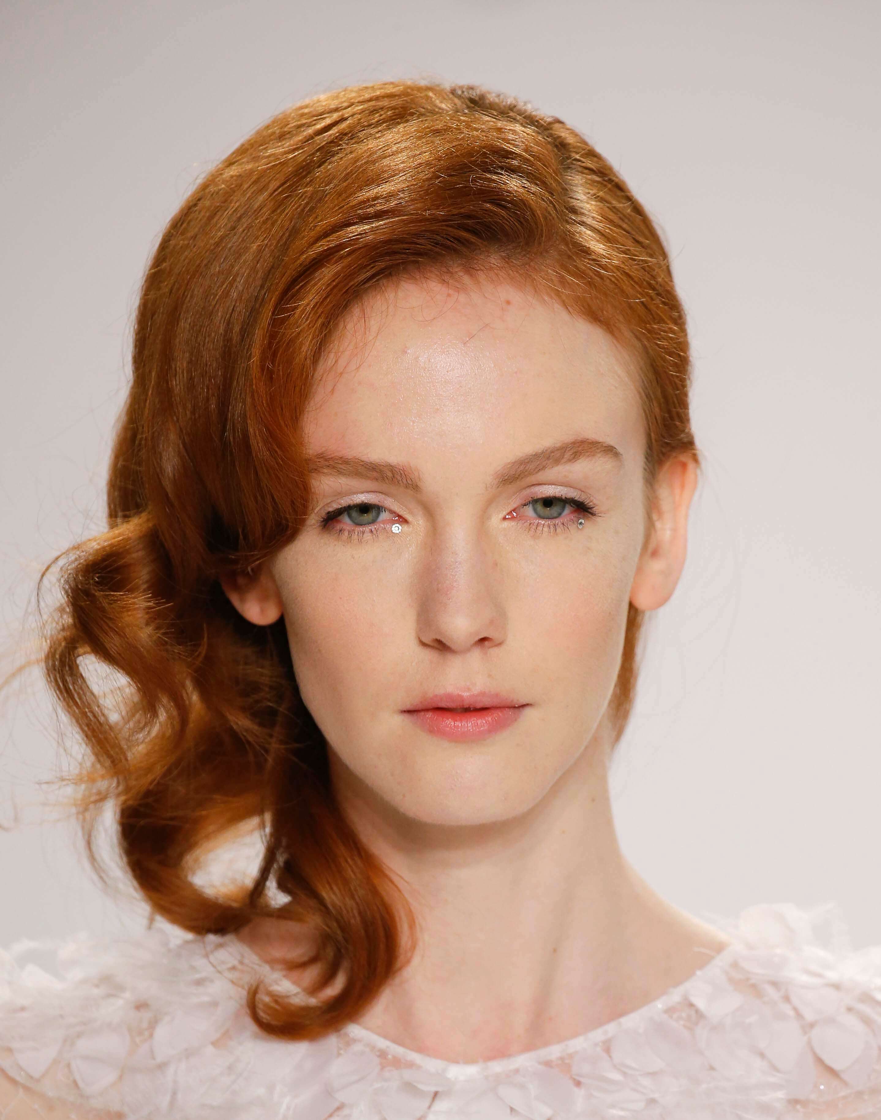 Wedding hairstyles for short hair: Woman with vintage wavy shoulder length copper hair wearing wedding dress on runway.