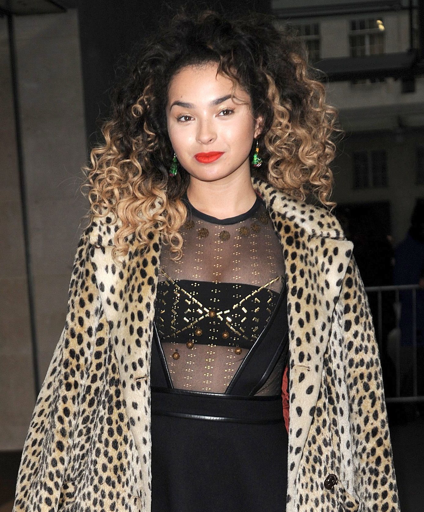 ella eyre wearing a leopard print coat with curly brown and blonde ombre hair