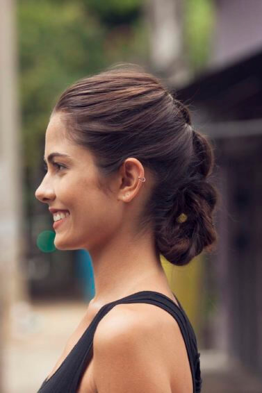 side view of a woman with a braided roll updo in dark brunette hair