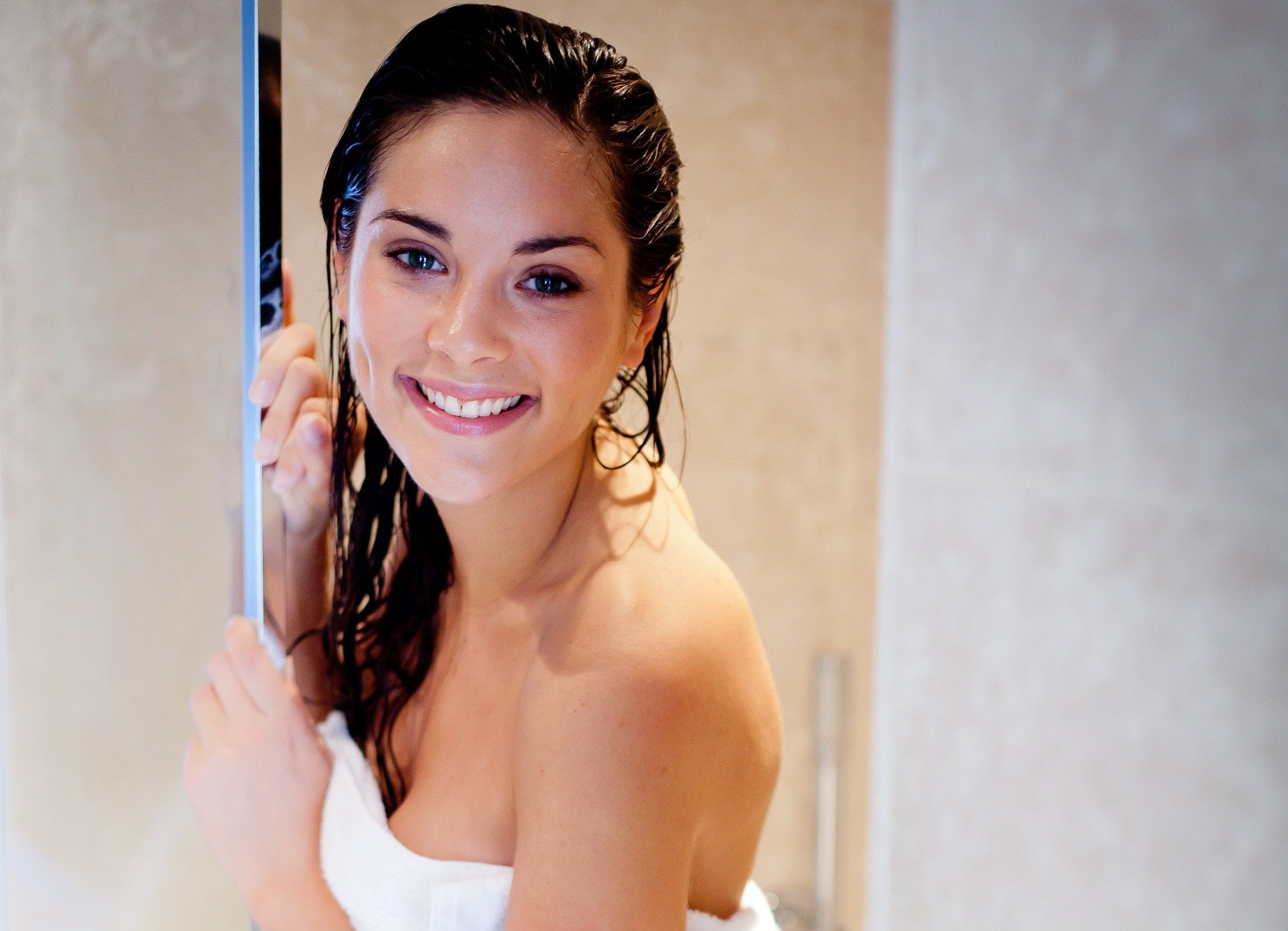 brunette woman in the shower in a towel with wet hair