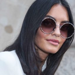 keratin treatment: close up shot of woman with dark smooth hair, wearing sunglasses with a white top, and posing for a street style shot