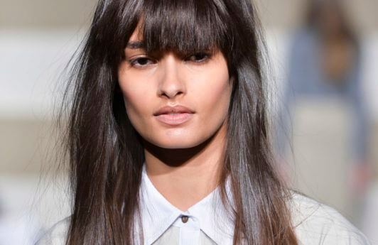 woman on the runway with long dark brown hair worn straight and with a full fringe cut in