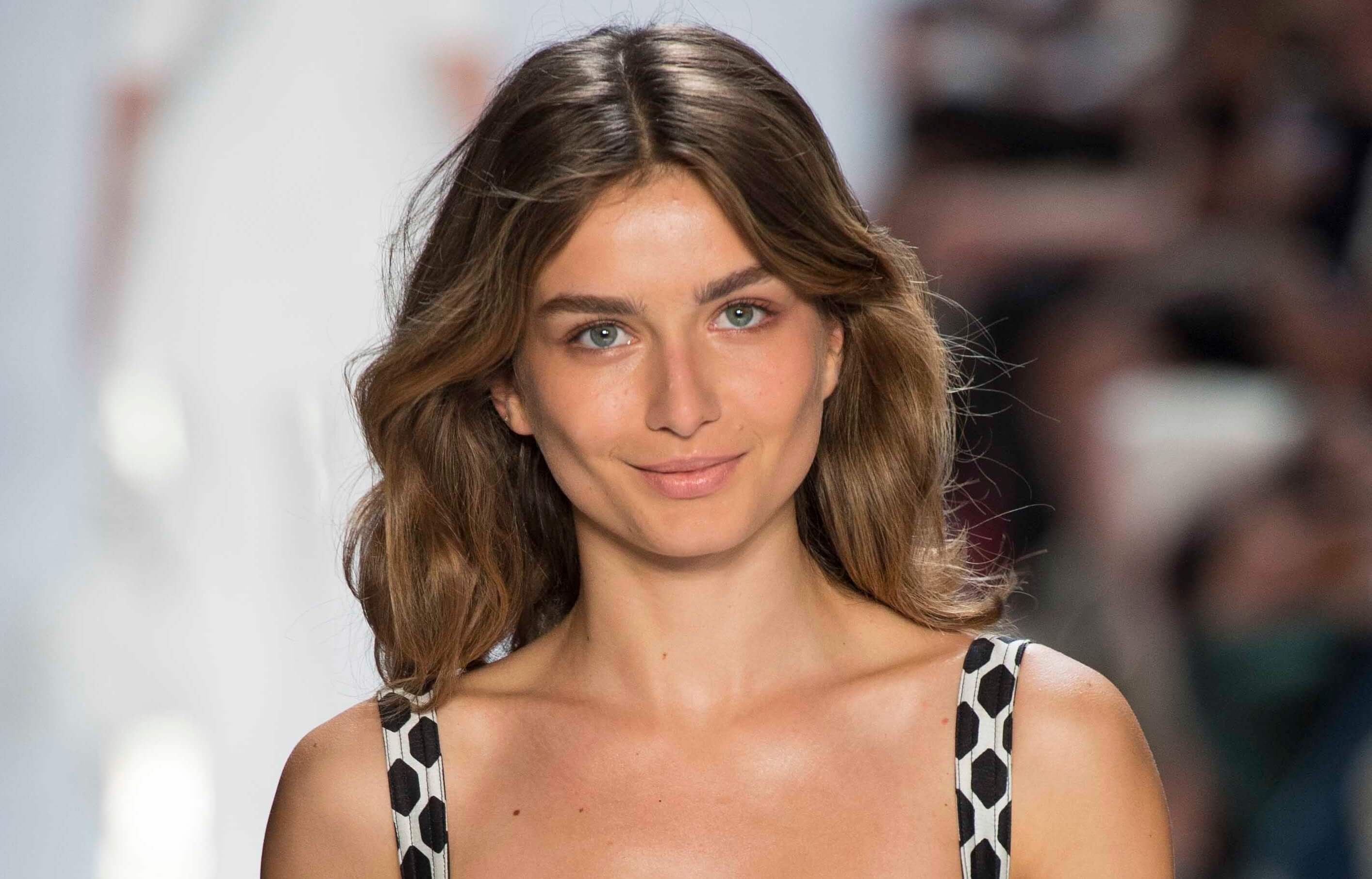Medium length hairstyles for fine hair: Woman with brown medium length wavy hair on runway.