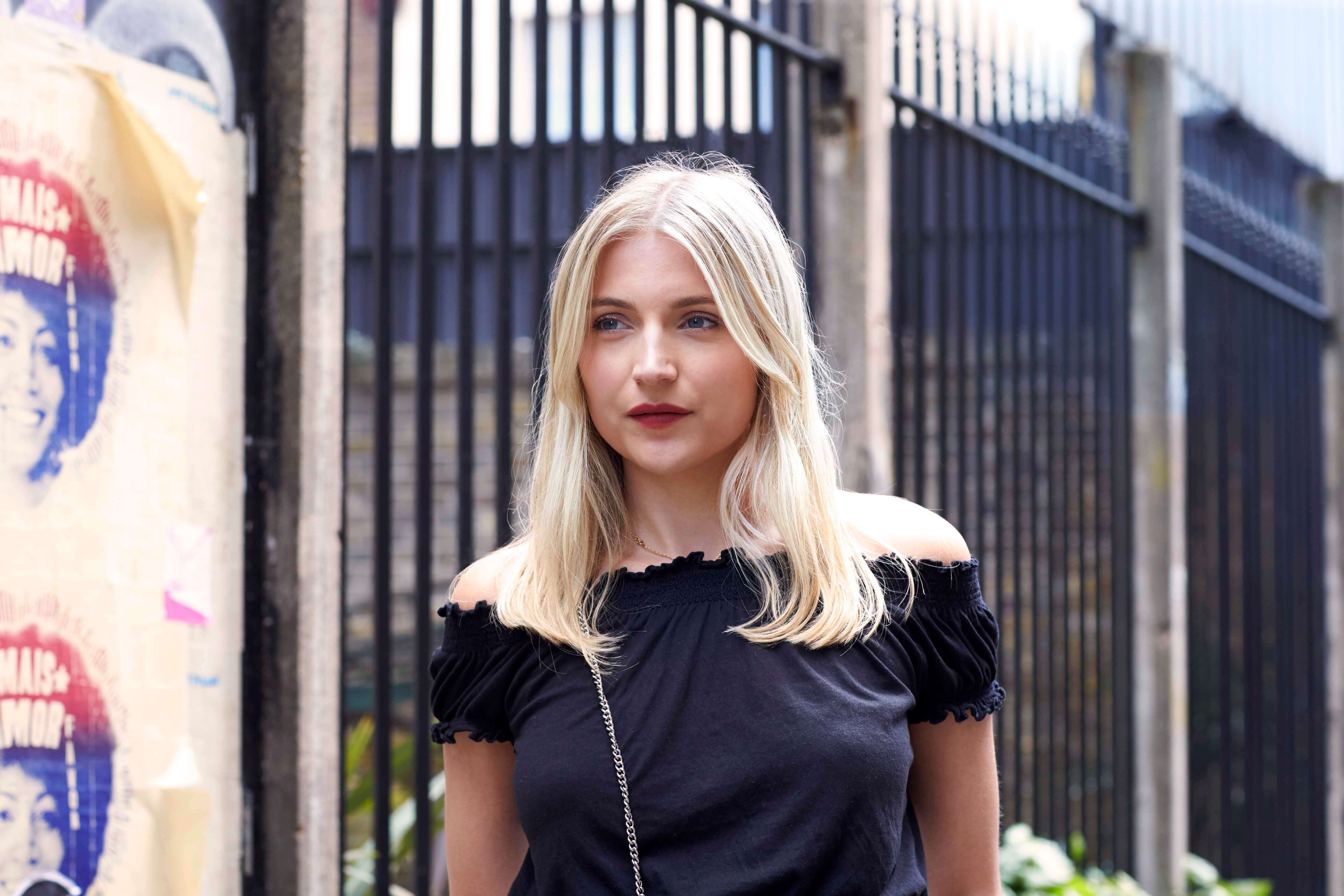 Medium length hairstyles for fine hair: Woman with slightly wavy blonde medium length hair wearing a black summer top.