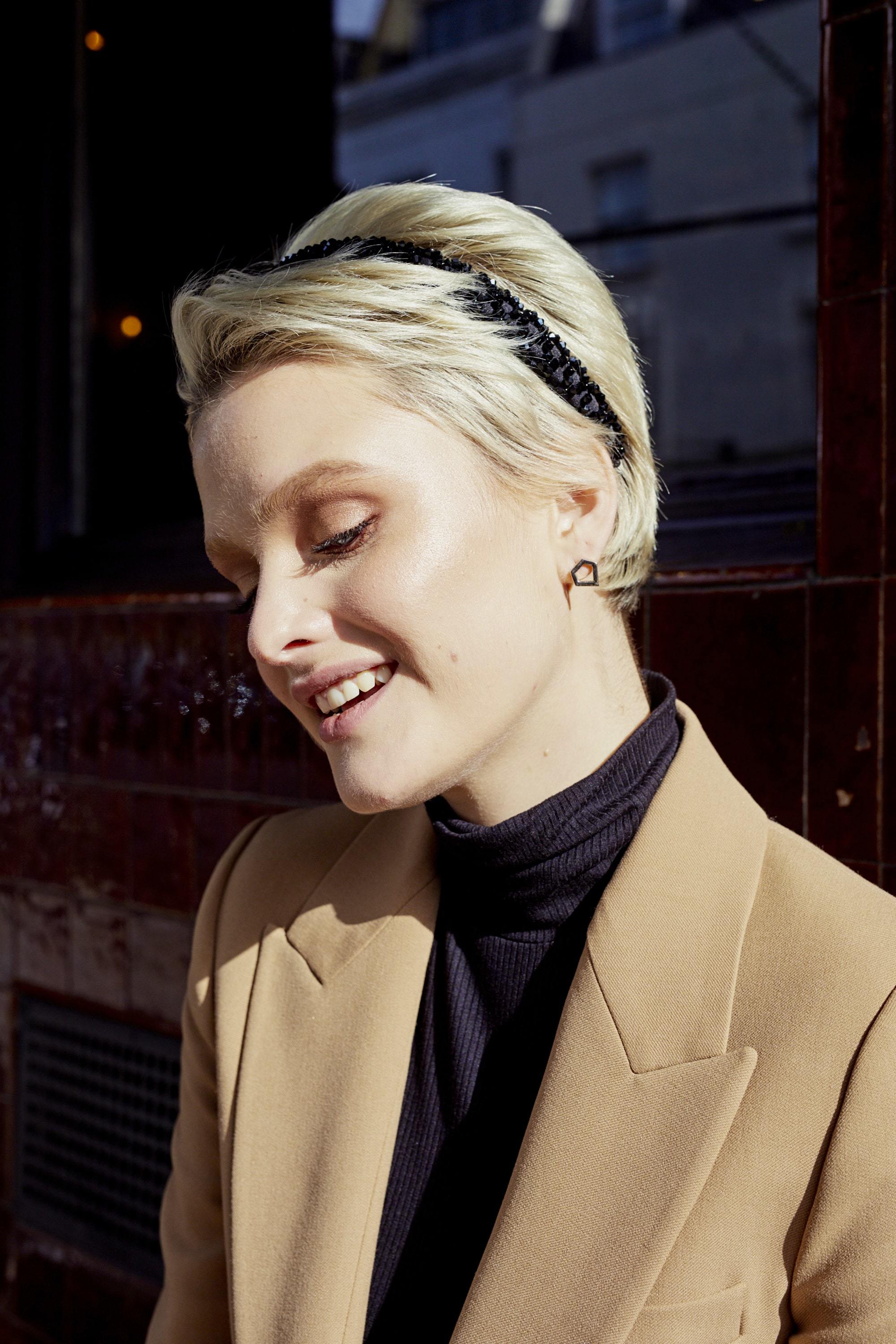 Woman with short platinum blonde pixie cut hair with a black headband