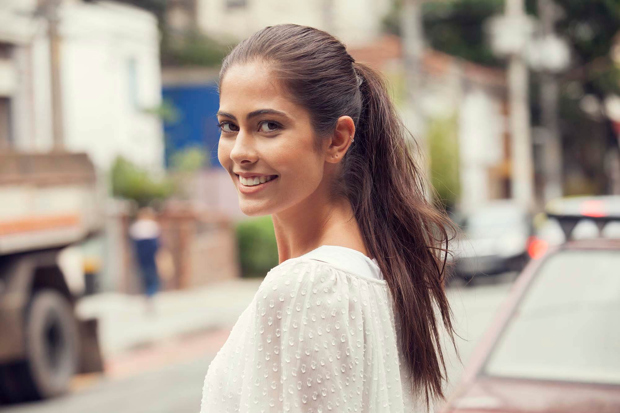how to prevent greasy hair happy brunette wearing a ponytail