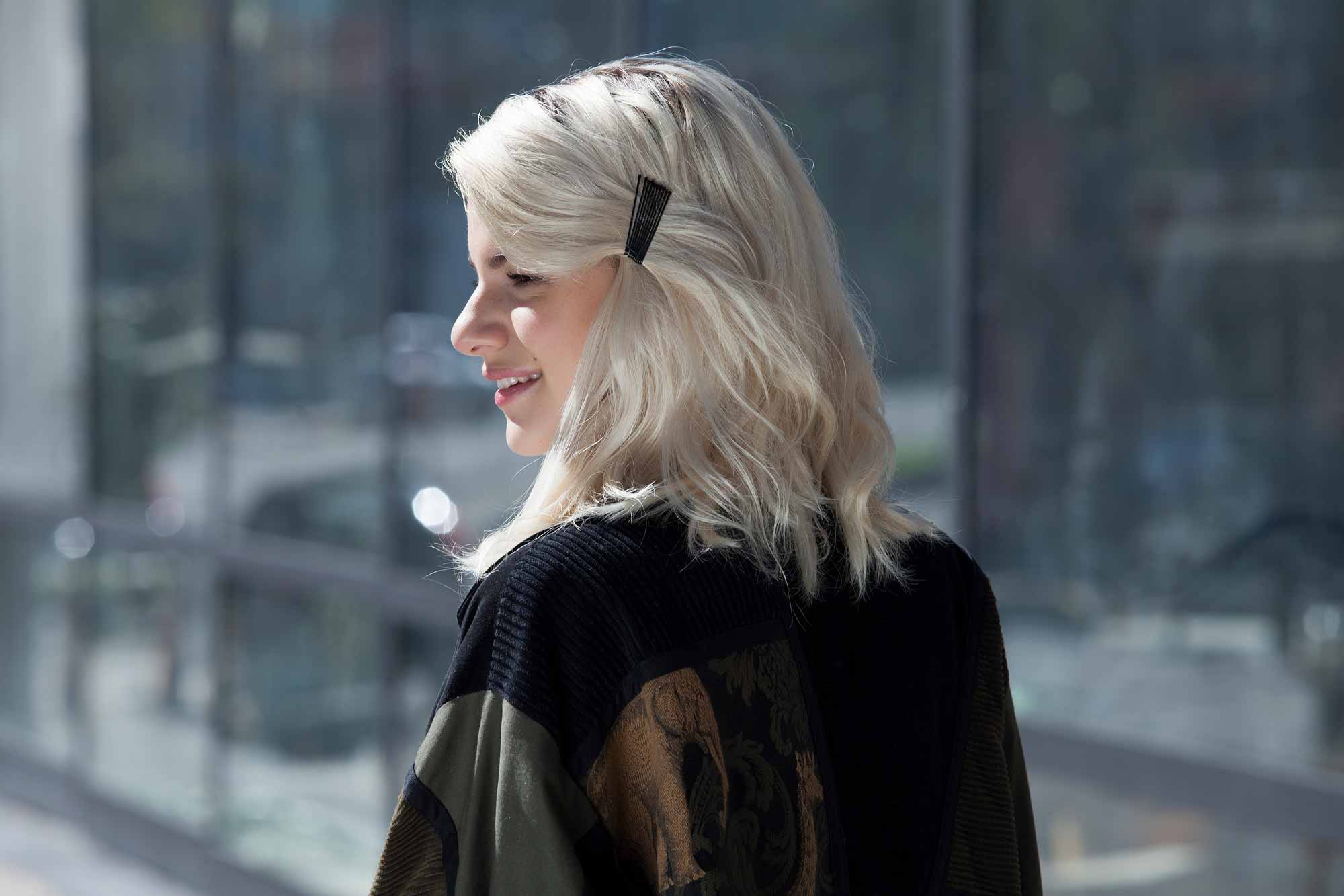 Bobby pin hairstyles: close up shot of a woman with platinum blonder hair with bobby pinned back fringe