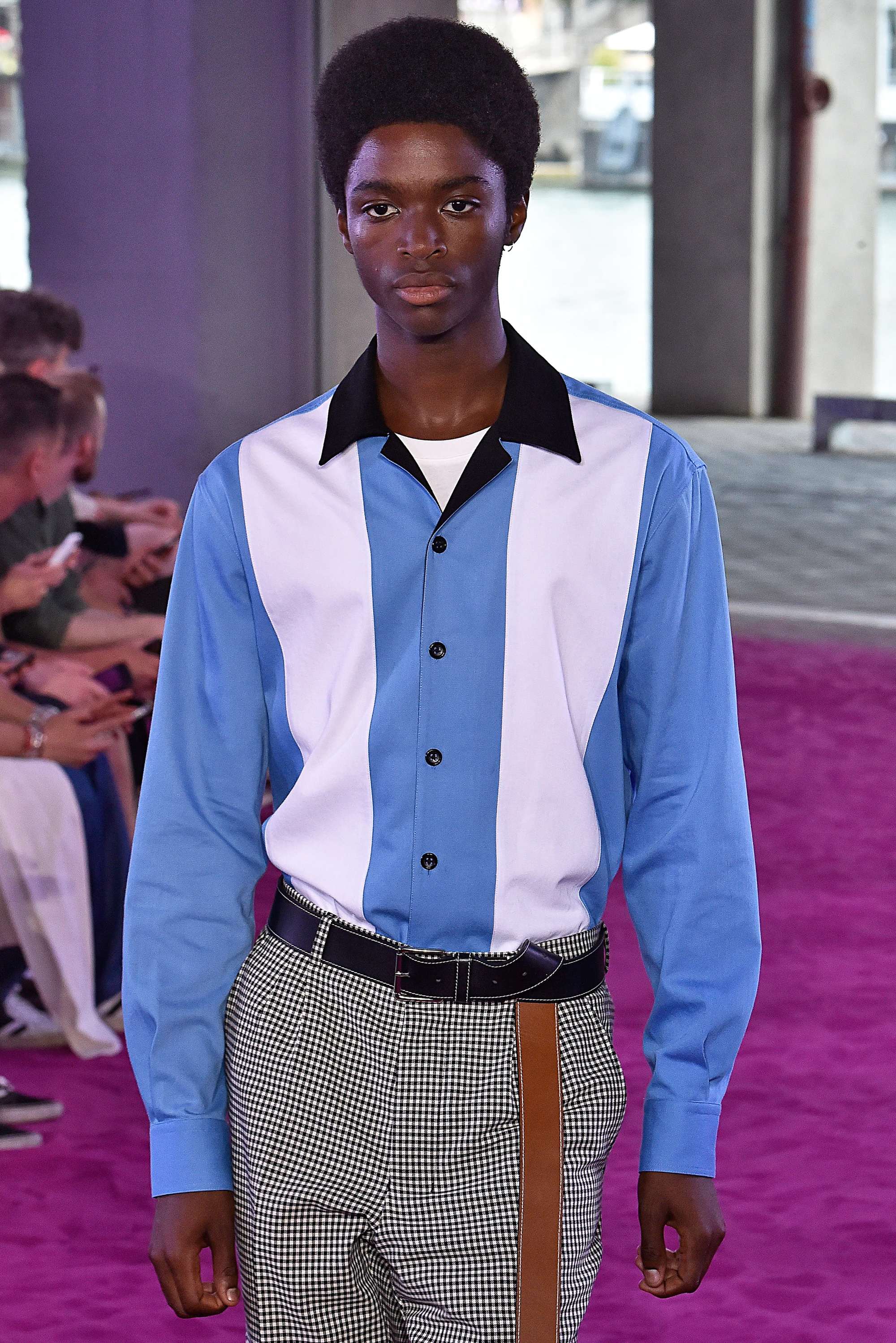 close up shot of black man with rounded power afro, wearing striped shirt and checked trousers on the AMI ss18 runway