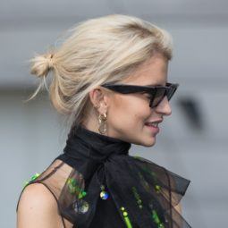 Best shampoo for fine hair: Caroline Daur with her short, bleach blonde fine hair styled into a messy bun updo, wearing sunglasses with black dress on the street