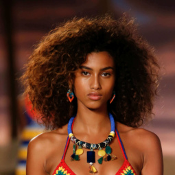 model with a big curly afro on the runway wearing tribal style clothing and jewellery
