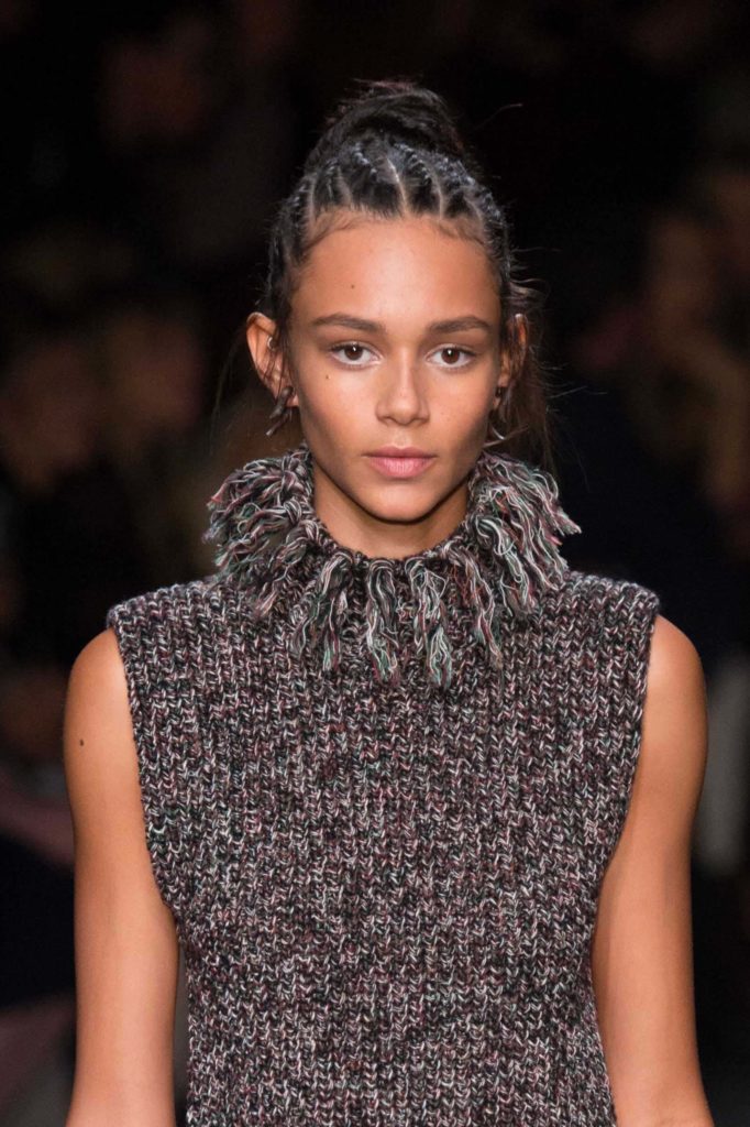 model with cornrows hairstyle on the runway wearing a grey knitted outfit