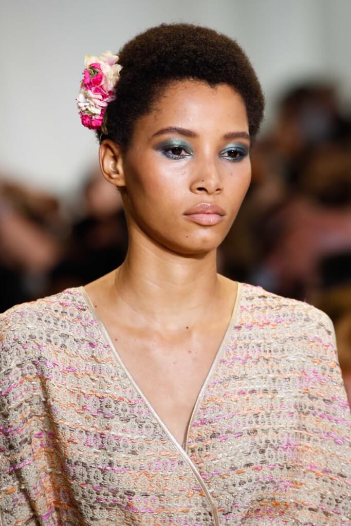 model with a mini afro hairstyle on the runway with a flower in her hair