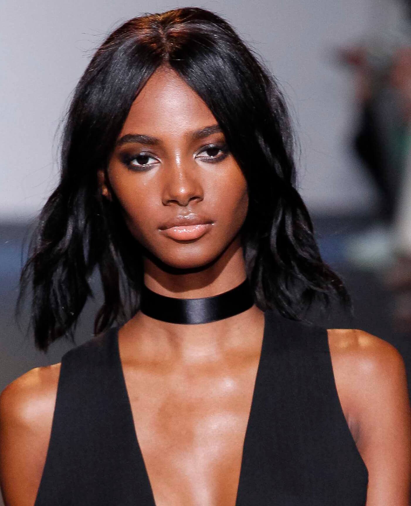 Hair straightening treatment: Model with relaxed dark brown shoulder length hair wearing a black vest and choker on runway.