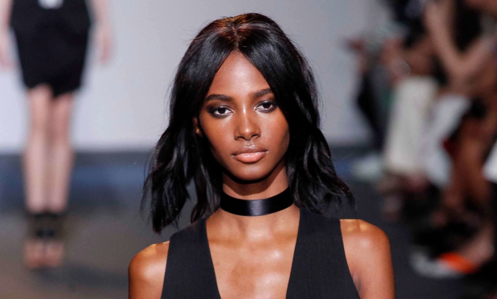 model with a middle parting and waves walking on the runway wearing an all black outfit and a black choker