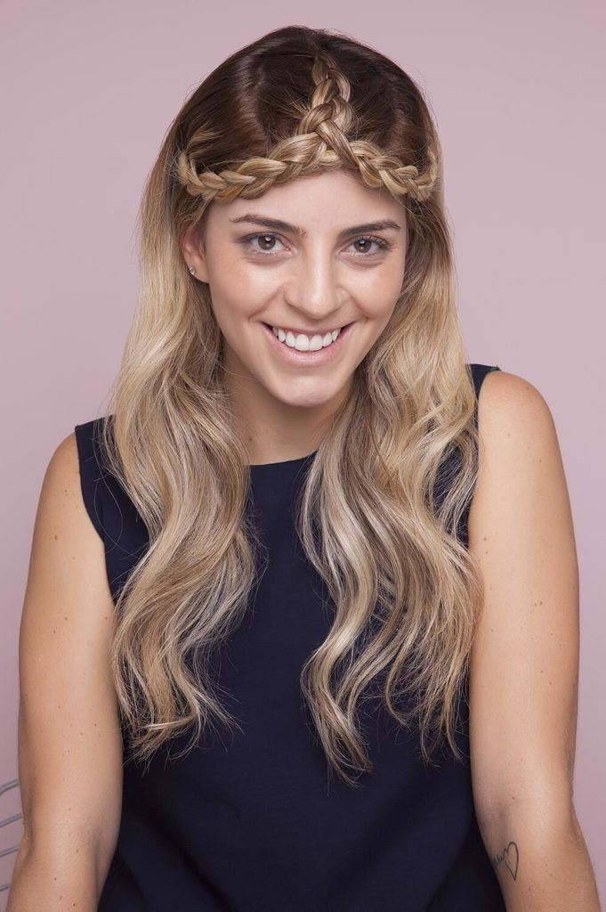 a woman with festival crown plait hair smiling on the purple background