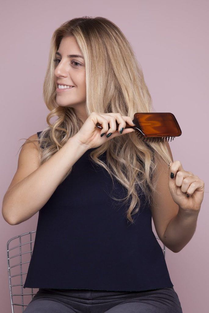 a curly woman combing her hair down