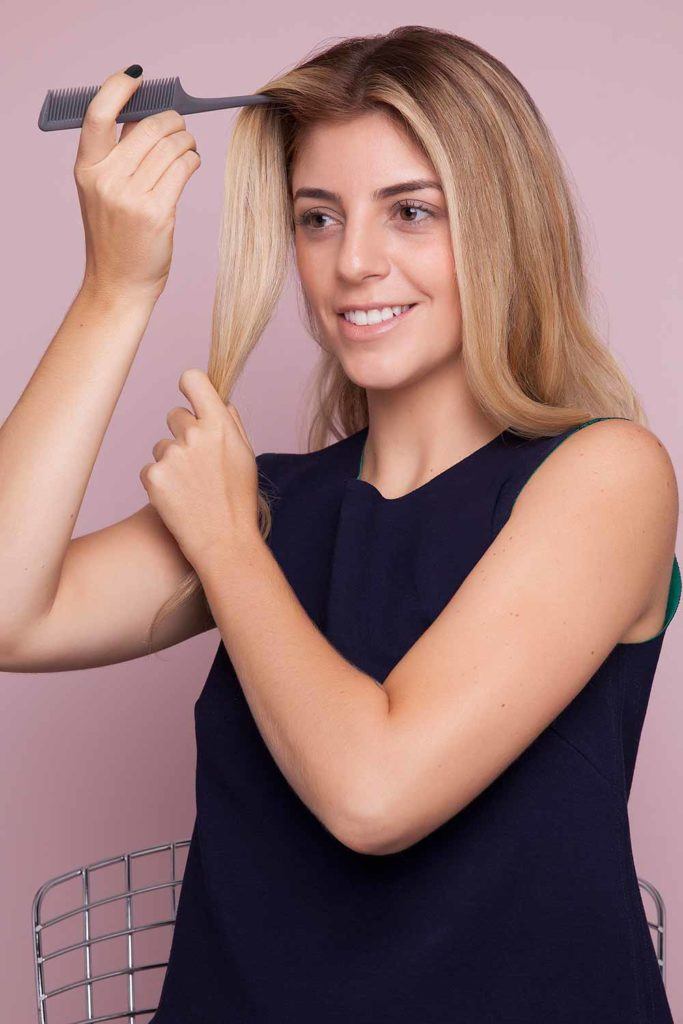 a wavy blonde woman combing her hair