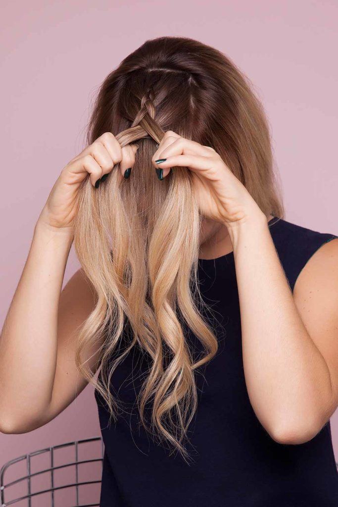 a blonde woman trying to make a braid