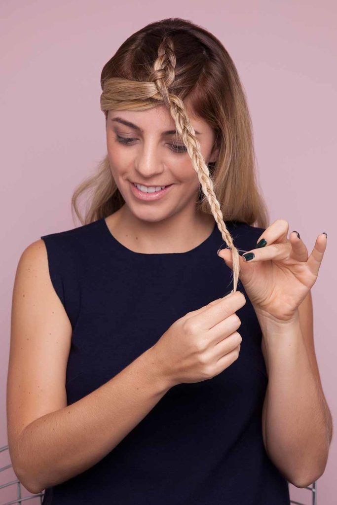a woman making a braid on her hair