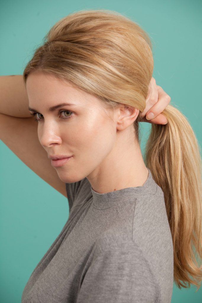 a blonde woman pulling back her hair