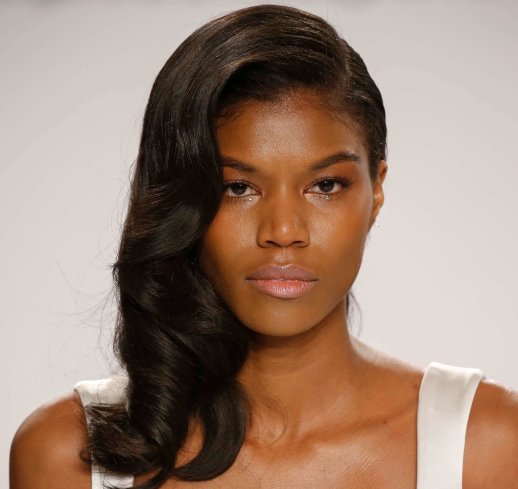 model with a side-swept waves hairstyle on the runway wearing a white outfit