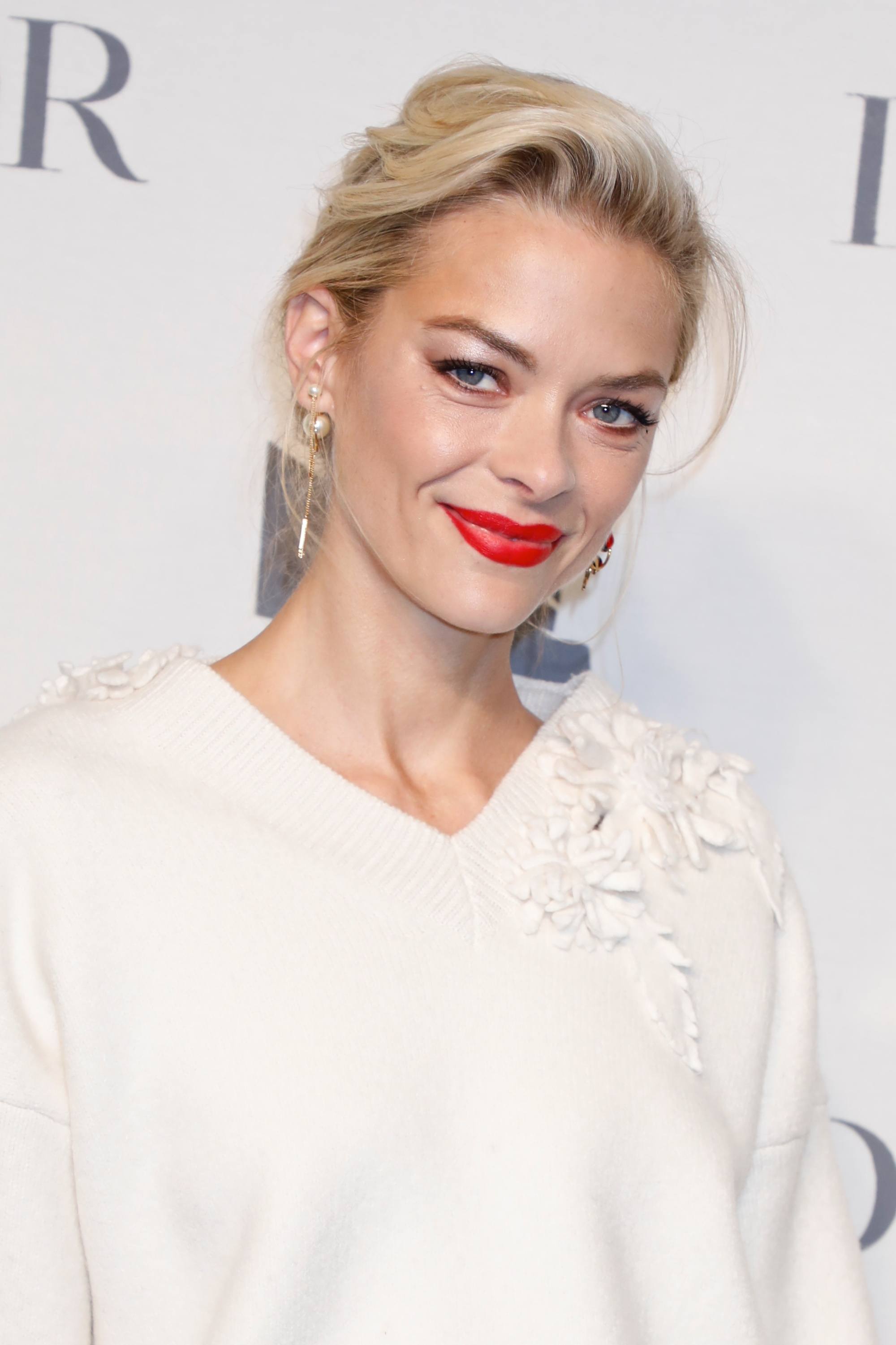 Jamie King with her golden blonde hair styled into a loose pomp, wearing all white on the red carpet