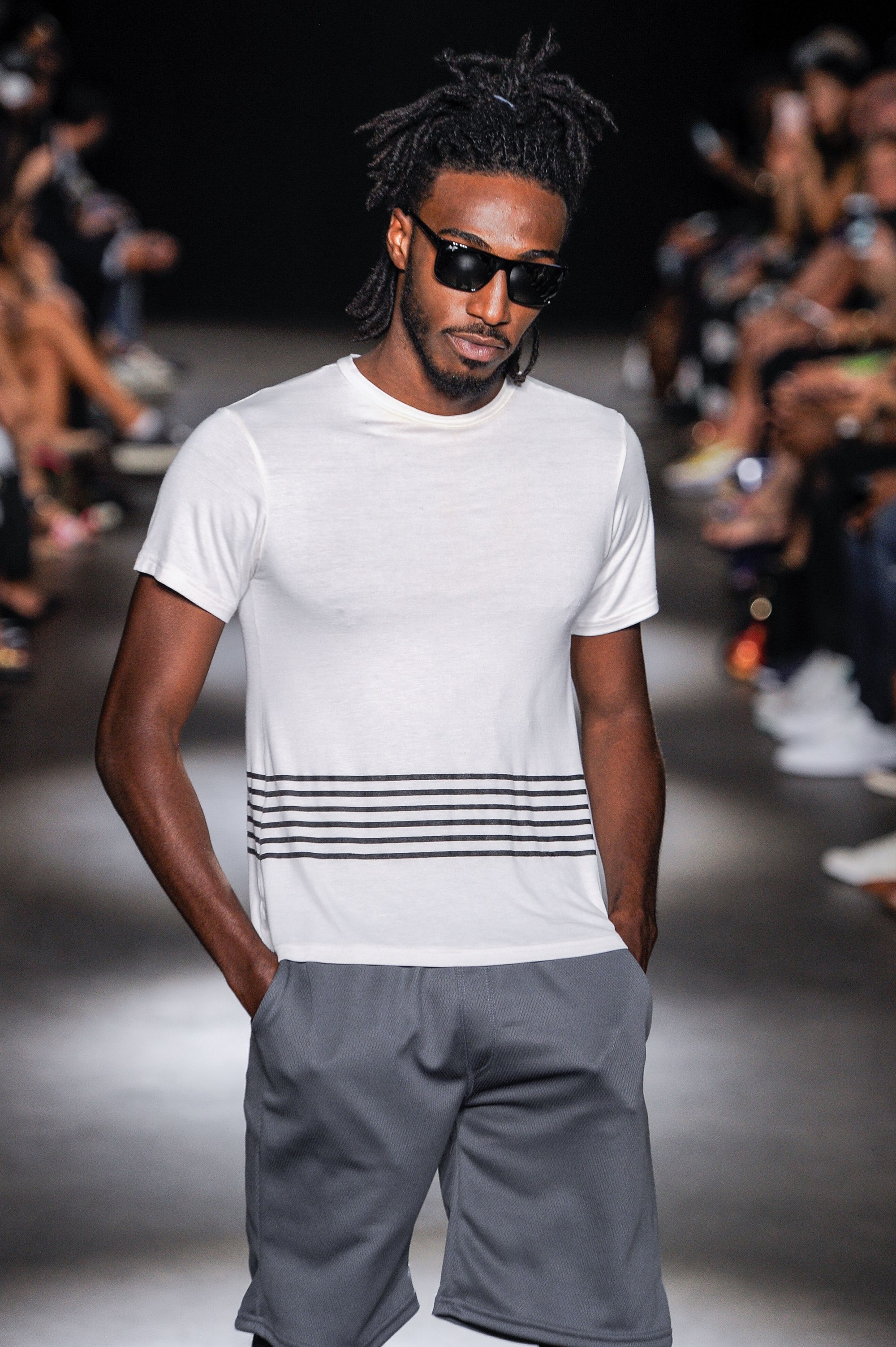 close up shot of black man with half up dreadlocks hairstyle, wearing white shirt and grey shirts on the grungy gentleman runway