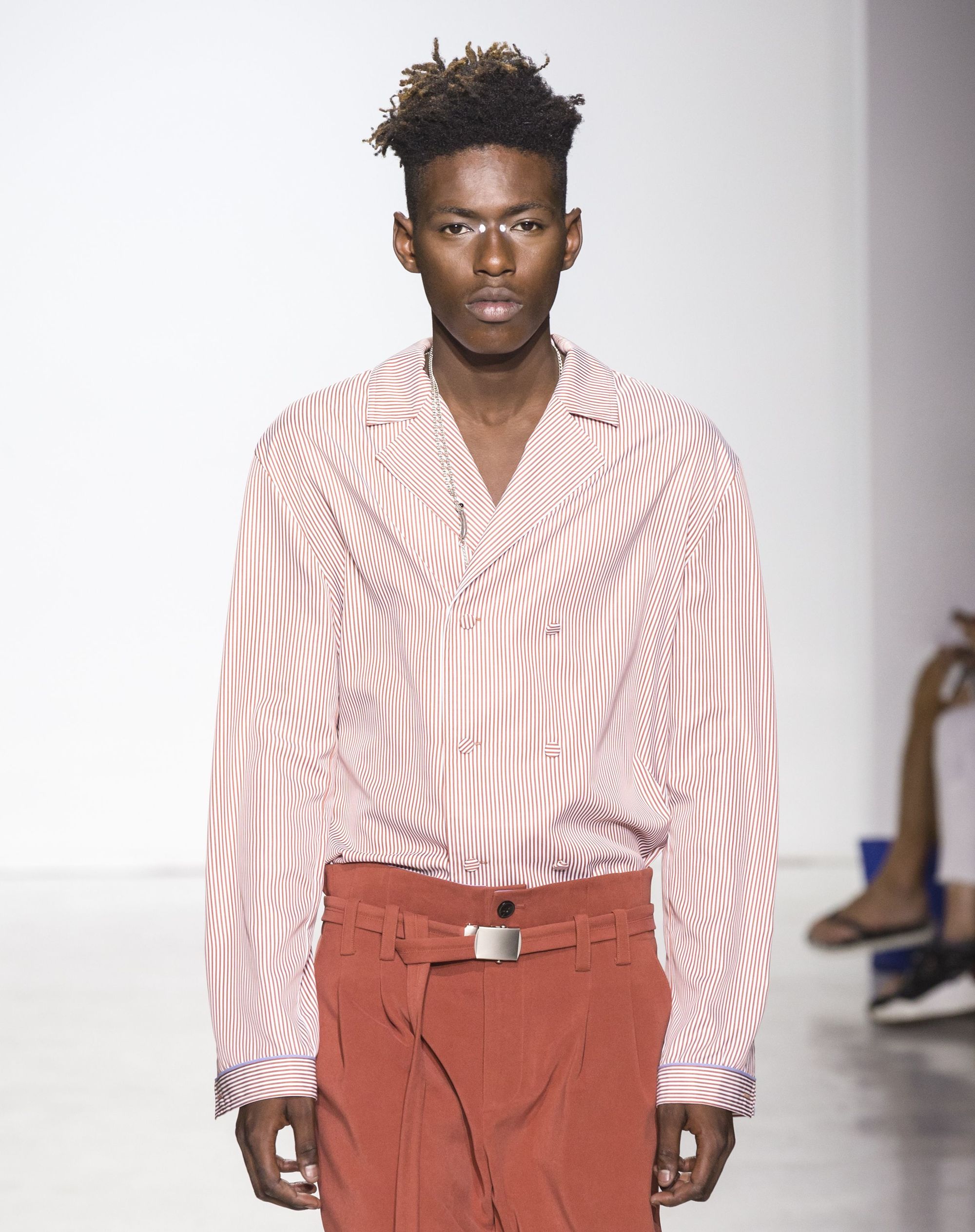 close up shot of black man with a high top skin fade hairstyle, wearing pink top and pink trousers on the general idea runway
