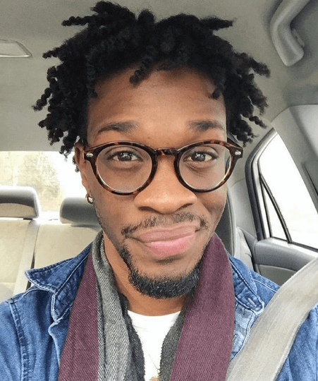 front view image of a black man with glasses and twist-out hair - black men hairstyles