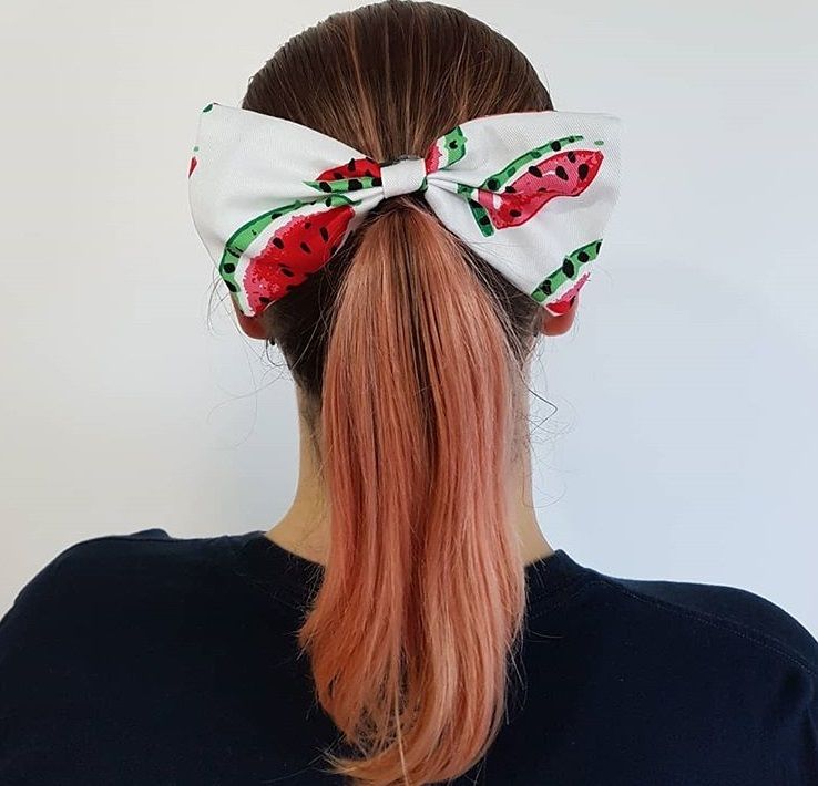 backshot of woman with a low ponytail that has a watermelon hair bow accessory on it