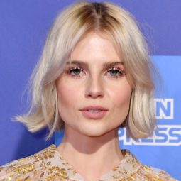 Hairstyles for thin hair: Lucy Boynton with her short platinum blonde hair styled into a short, flipped bob with Bardot bangs, wearing a floral top on the red carpet