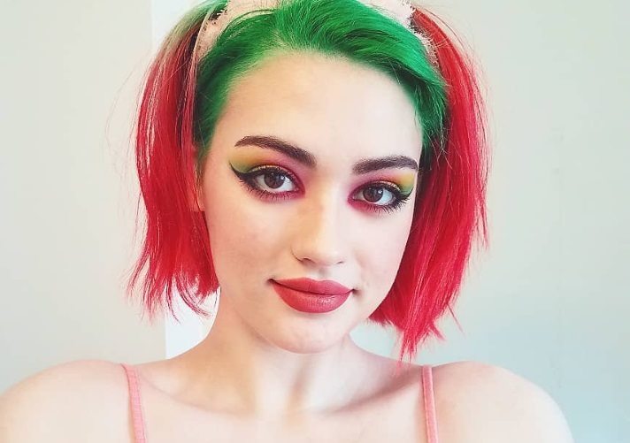 close up shot of woman with chin length green and red two tone hair wearing a headband
