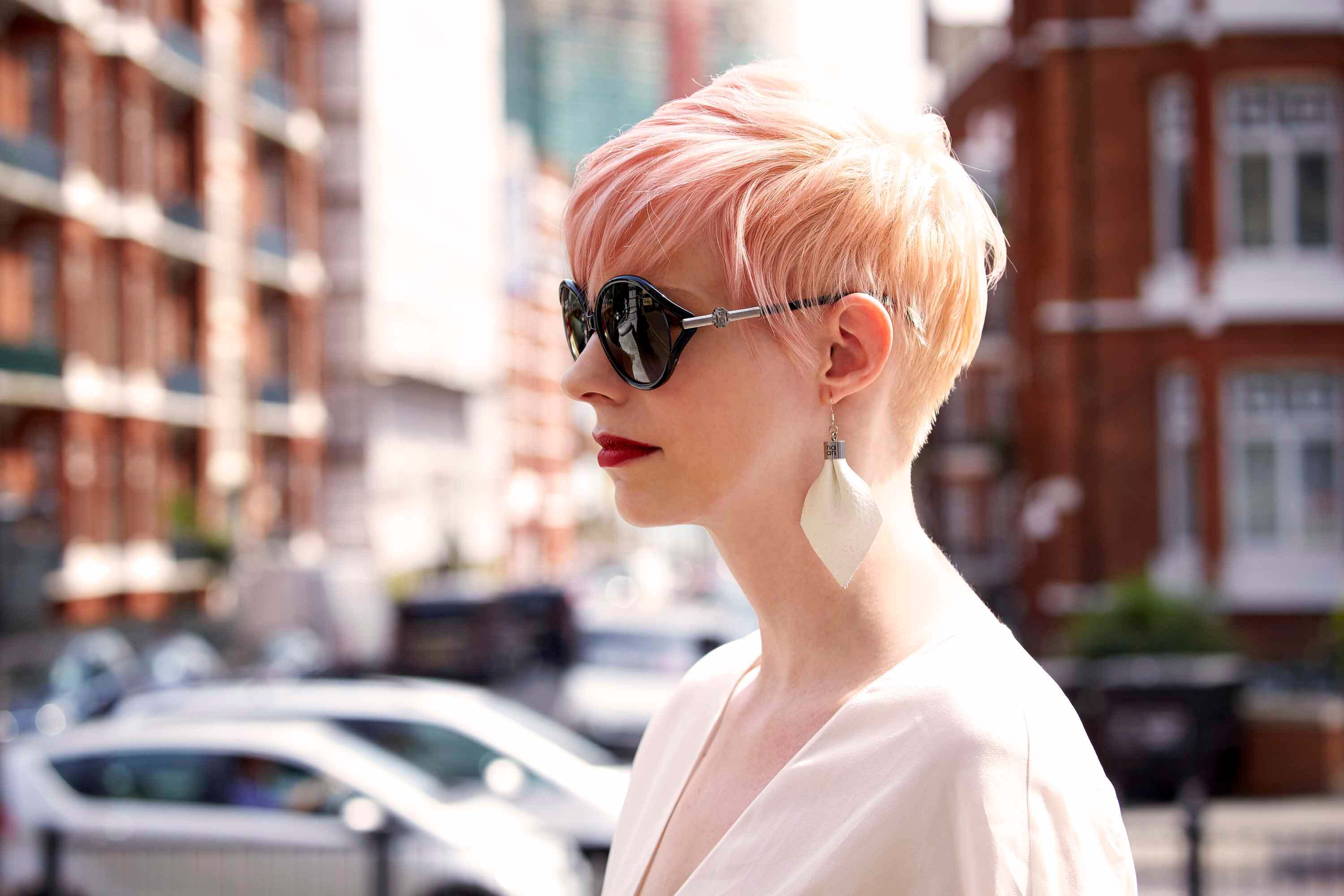 Short hairstyles for fine hair: Woman with pastel pink long feathered pixie cut wearing sunglasses.