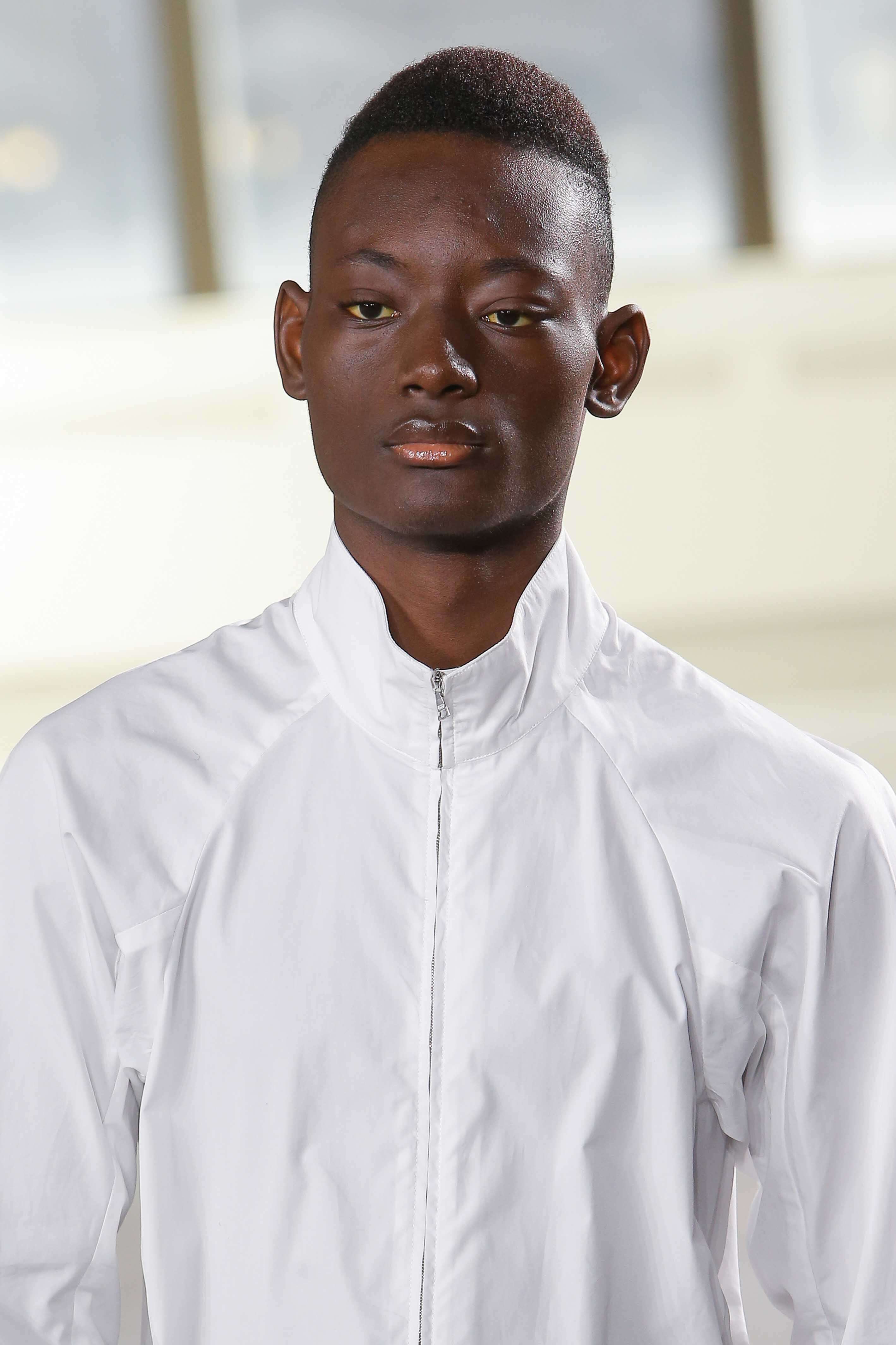 close up shot of a black male model on the runway with south of france haircut, wearing white top