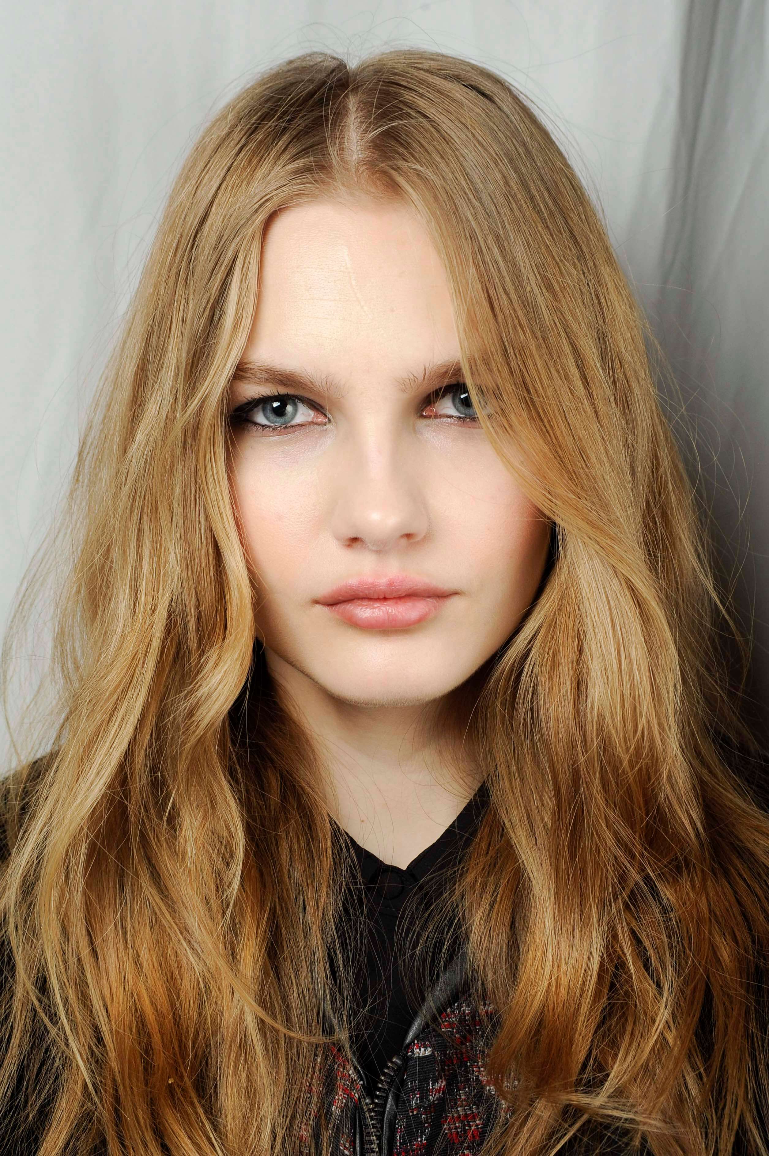 Shades of blonde hair: Woman with wavy warm blonde long hair wearing a black top.