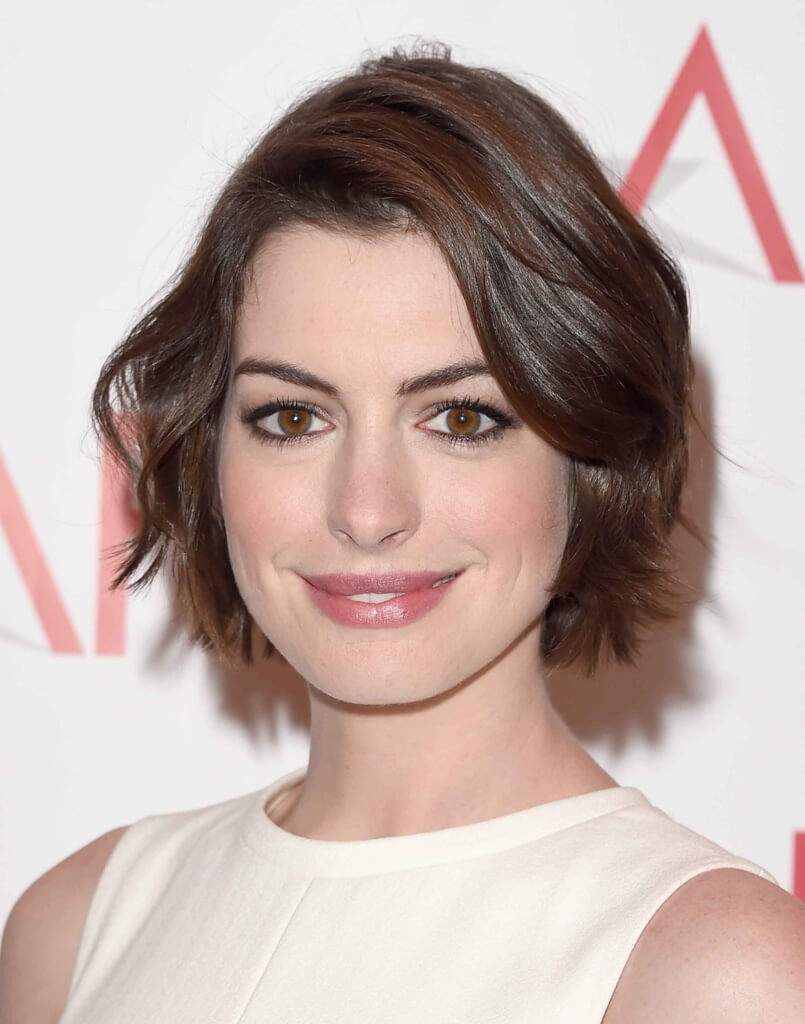anne hathaway with a short wavy bob wearing a white dress
