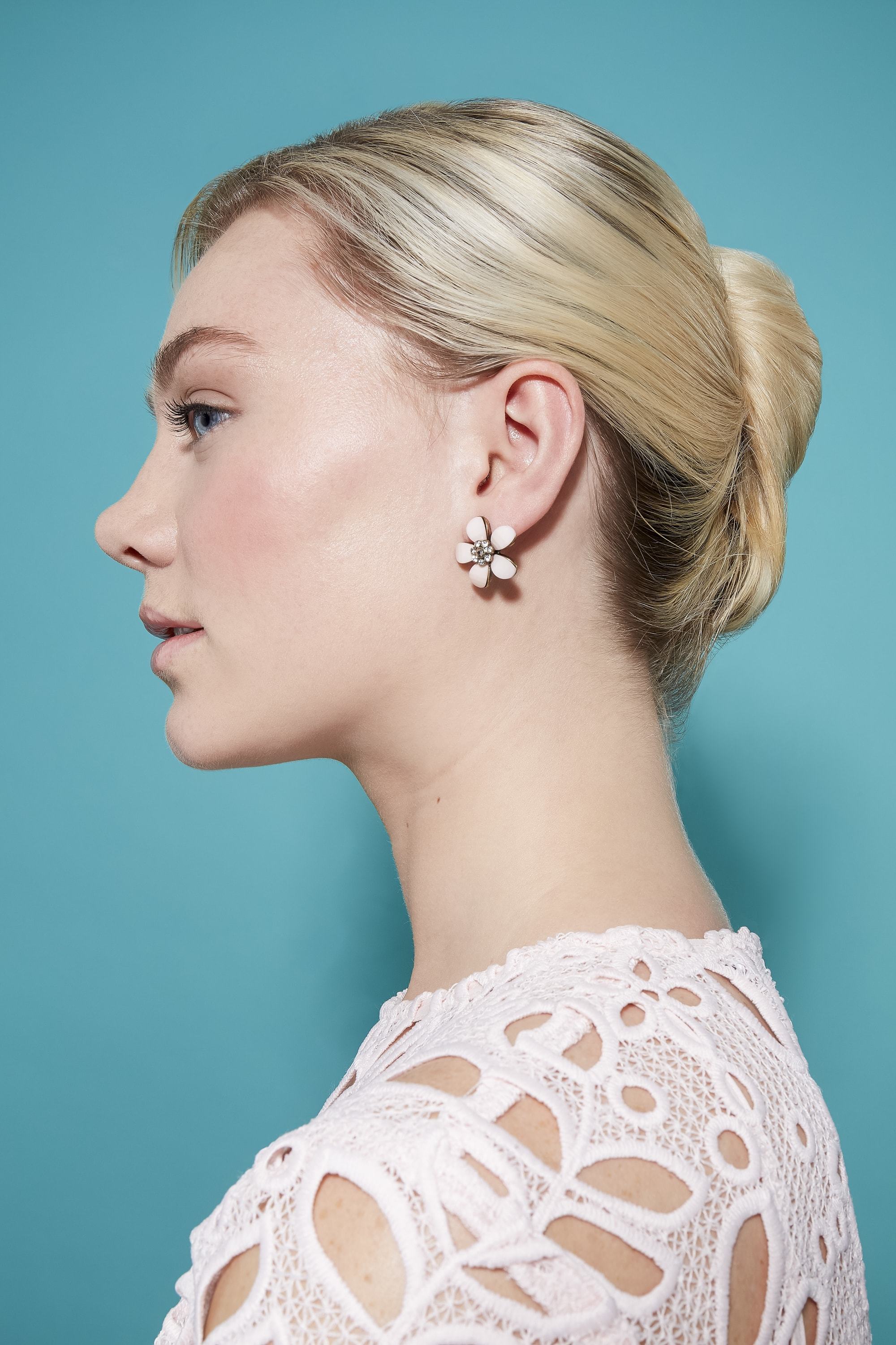 side view of model with blonde hair styled into a french twist updo wearing a white top