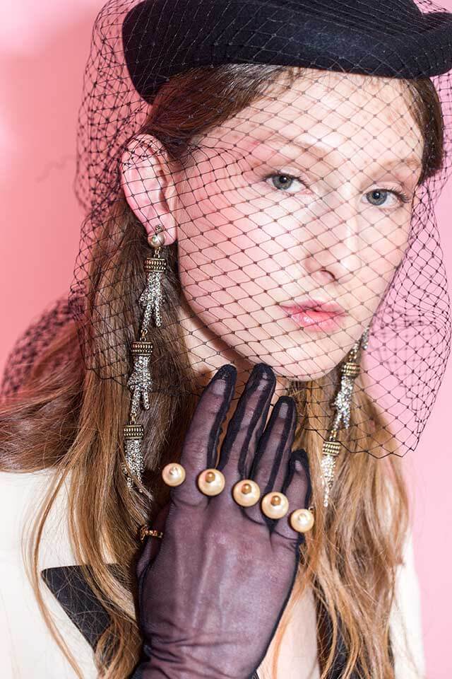 model at the Gucci AW16 show wearing a black hairnet iver her mousey brown hair with long earrings and a purple embellished glove