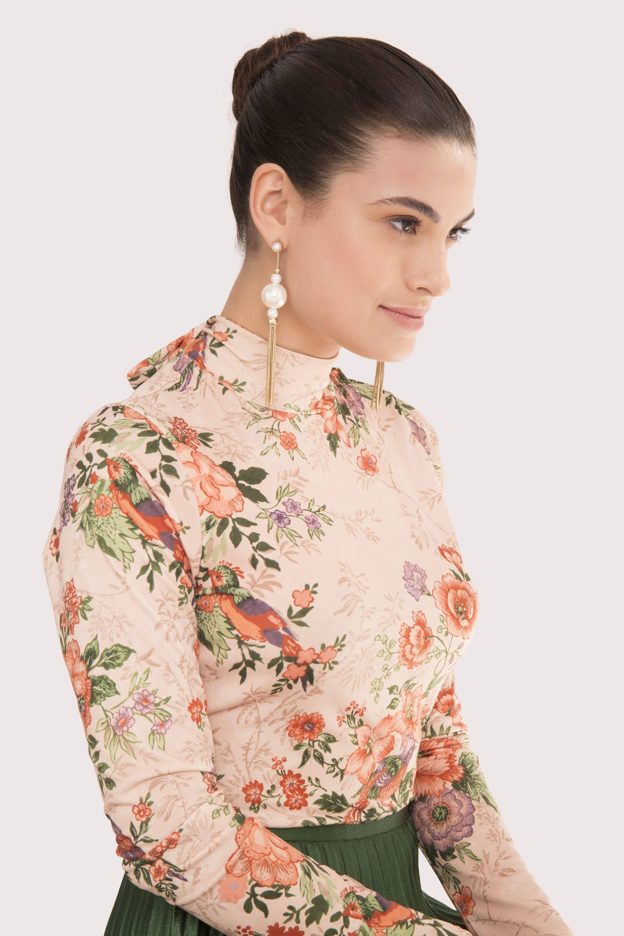 model with brown hair styled into high smooth formal bun updo wearing light coloured floral top