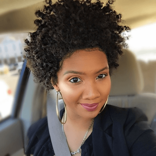 close up shot of woman with tapered afro hairstyles, wearing hoop earrings and black jacket
