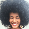 close up shot of woman with classic halo afro hairstyle, wearing earrings and smiling