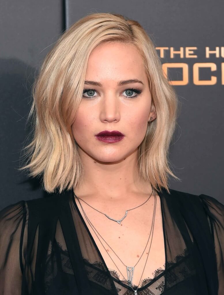 Jennifer Lawrence with a blonde wavy bob in side parting on the red carpet wearing a sheer black dress