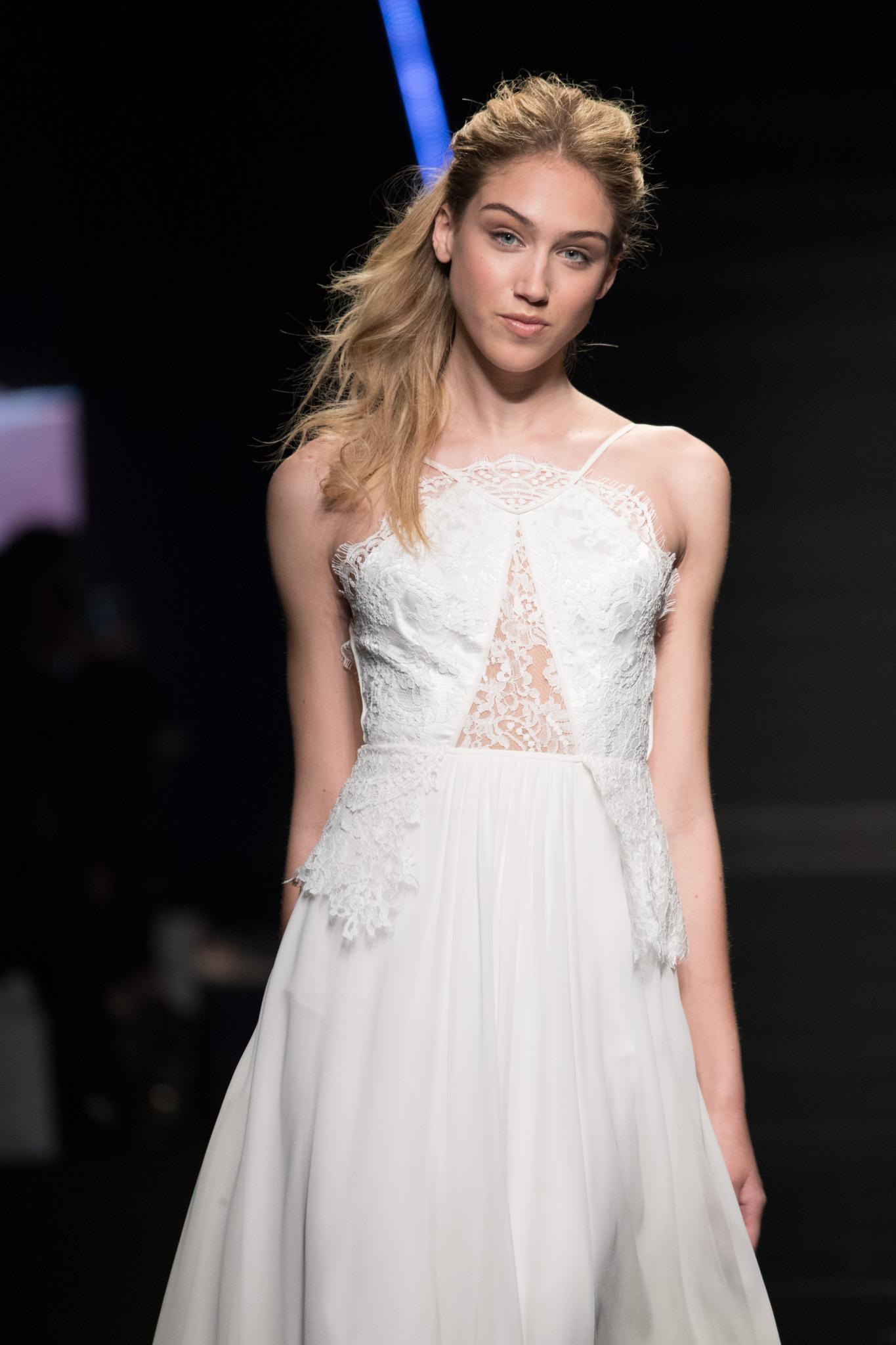 model on bridal runway with long dirty blonde hair in textured high ponytail with ends swept over one shoulder wearing wedding dress
