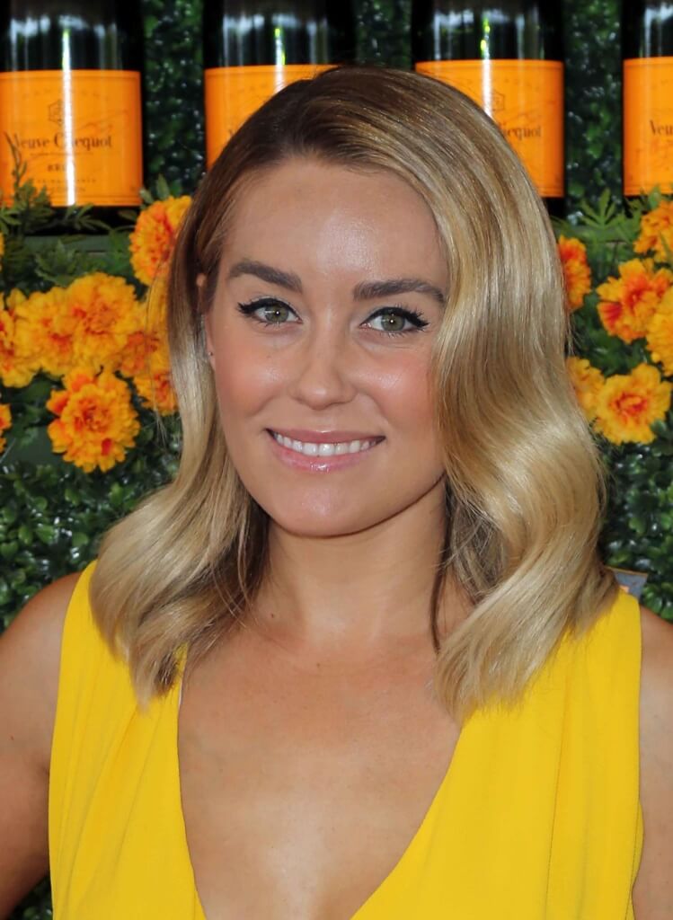 wavy blonde bob on Lauren Conrad wearing a yellow dress on the red carpet with orange flowers in the background